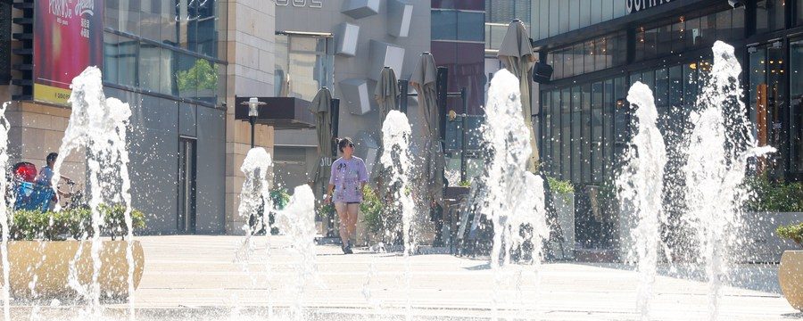 Cidadã caminha por fonte em meio à alta temperatura no distrito de Minhang, Shanghai, no leste da China, em 10 de julho de 2022. (Xinhua/Fang Zhe)
