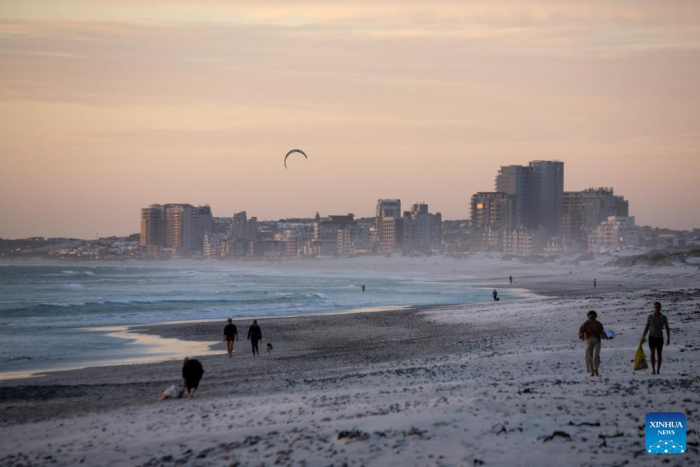People walk on Sunset Beach at sunset in Cape Town, South Africa, on March 26, 2022. (Xinhua/Lyu Tianran)