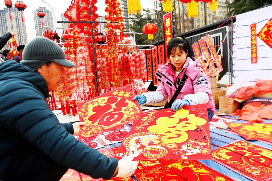 Pessoas compram decorações para a chegada do Ano Novo Lunar Chinês em um mercado em Qingdao, Província de Shandong, no leste da China. (Xinhua/Yu Fangping)