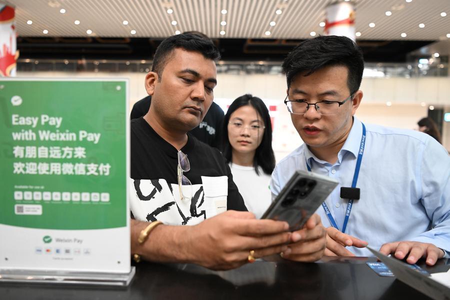 Tencent lança app de pagamentos para turistas estrangeiros na China Um passageiro indiano (à esquerda) pergunta sobre o WeChat Pay, da Tencent, uma das principais plataformas de pagamento móvel da China, no Terminal 2 do Aeroporto Internacional Baiyun de Guangzhou, em Guangzhou, Província de Guangdong, no sul da China, 3 de abril de 2024. (Xinhua/Deng Hua)