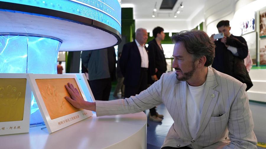 Visitantes estrangeiros conhecem reflorestamento de 40 anos em Xinjiang O ator e apresentador de televisão norte-americano Steven Weathers observa uma exposição no Memorial Kekeya, na cidade de Aksu, na Região Autônoma Uigur de Xinjiang, no noroeste da China, em 14 de outubro de 2026. (Xinhua)